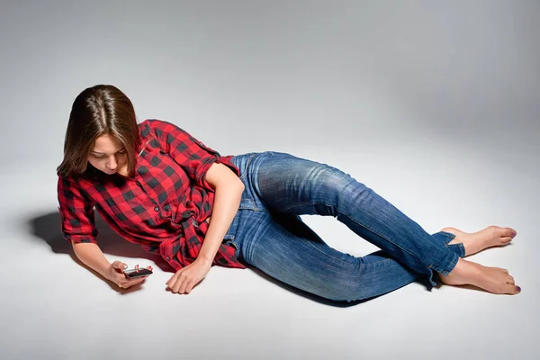 Sonriente chica adolescente sentada descalza en el suelo sonriendo a la cámara — Foto de Stock