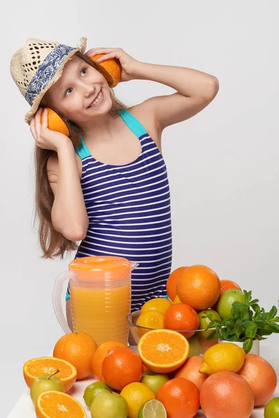 Girl in swimsuit and summer hat with citrus fruits making headphones — Stock Photo, Image