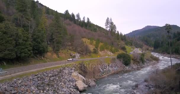 Asfalt kronkelige weg gaat langs de rivier van de berg — Stockvideo