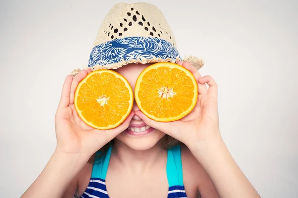 Girl in swimsuit making fake eyeglasses with oranges — Stock Photo, Image