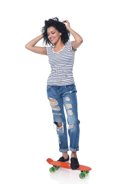 Felice femmina in jeans angosciati con skateboard — Foto Stock