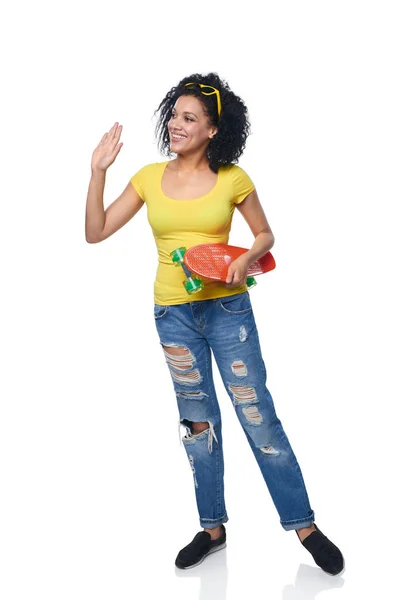 Mulher feliz em jeans angustiados com skate — Fotografia de Stock