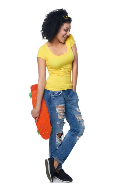 Mulher feliz em jeans angustiados com skate — Fotografia de Stock