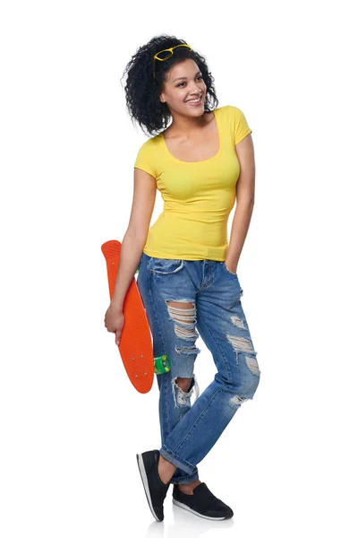 Gelukkige vrouw in distressed jeans met skateboard — Stockfoto