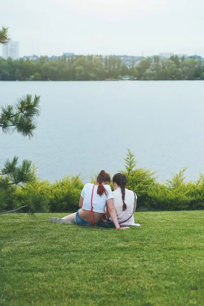 Dos amigas sentadas en la hierba en un parque —  Fotos de Stock
