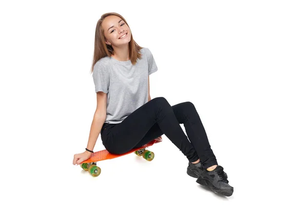 Teen dziewczyna w pełnej długości siedzi na pokładzie skate — Zdjęcie stockowe