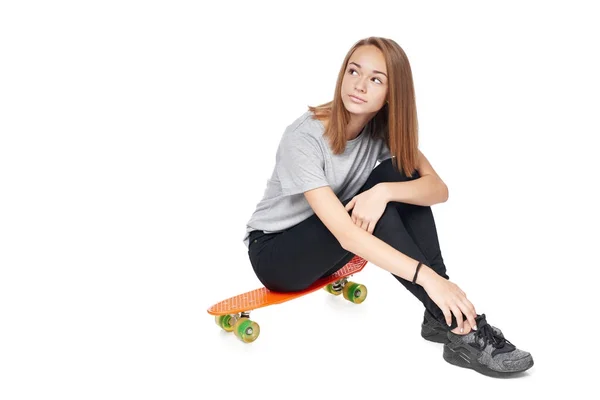 Teen dziewczyna w pełnej długości siedzi na pokładzie skate — Zdjęcie stockowe