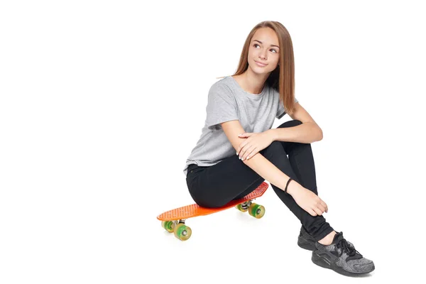 Tiener meisje in volle lengte zittend op skate board — Stockfoto