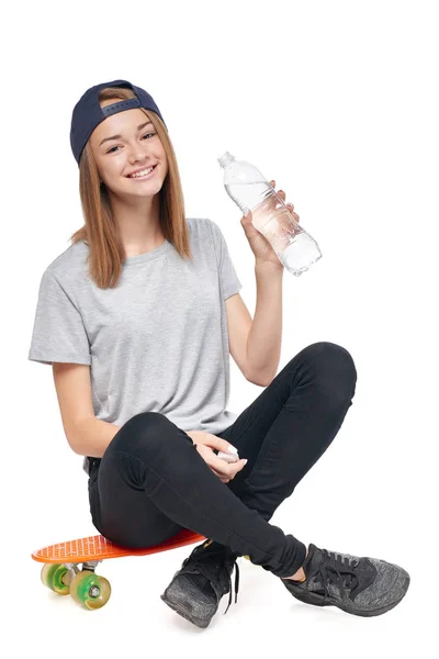 Adolescente assise sur une planche à roulettes avec bouteille d'eau — Photo