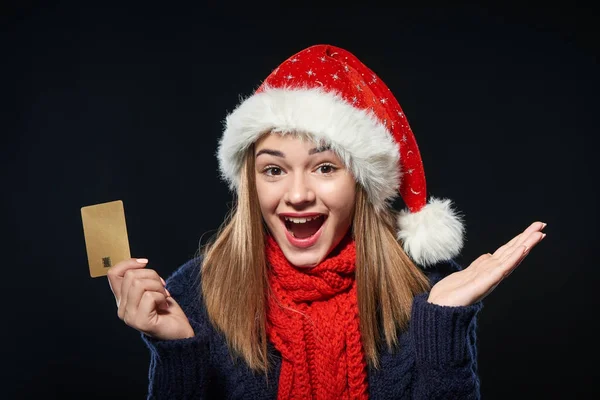 Chica sorprendida en Santa sombrero con tarjeta de crédito en blanco — Foto de Stock