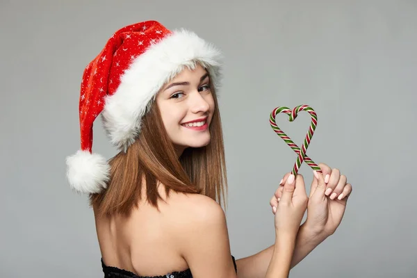 Girl in Santa hat holding Christmas candies in heart shape — Stock Photo, Image