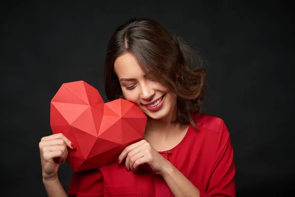 Hymyilevä nainen, jolla on punainen monikulmio sydämen muoto — kuvapankkivalokuva