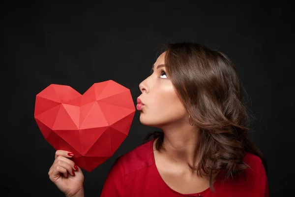 Femme souriante tenant une forme de coeur polygonale rouge — Photo