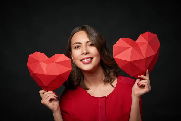 Femme souriante tenant deux formes de coeur polygonales — Photo