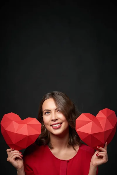 Mujer sonriente sosteniendo dos forma de corazón poligonal —  Fotos de Stock