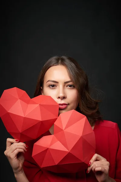 Femme souriante tenant une forme de coeur polygonale rouge — Photo