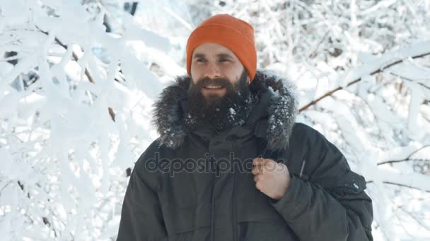 Seorang pria tersenyum dan melambaikan tangan di depan kamera di hari yang bersalju di musim dingin — Stok Video