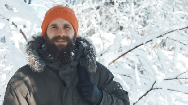 Hombre sonriendo y saludando a la cámara al aire libre en un día nevado de invierno — Vídeos de Stock