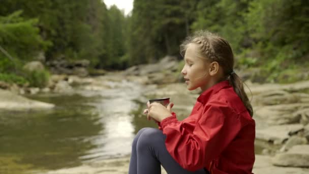Niño sentado en la orilla del río de montaña — Vídeos de Stock