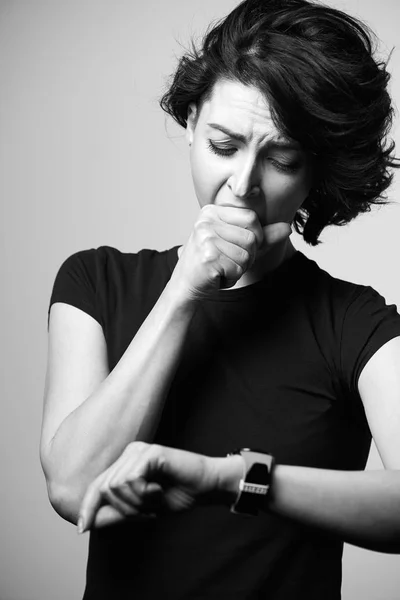 Женщина смотрит на часы и зевает — стоковое фото