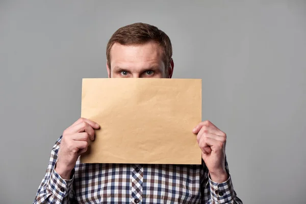 Homem barbudo segurando envelope marrom em branco — Fotografia de Stock