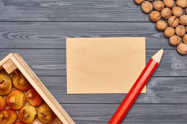 Wooden box with yellow pears and walnuts on gray planks — Stock Photo, Image