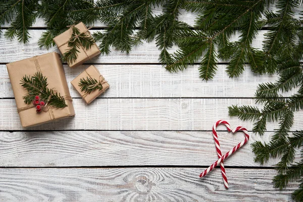Kerst frame gemaakt van sparren takken met geschenkdoosjes op witte planken — Stockfoto