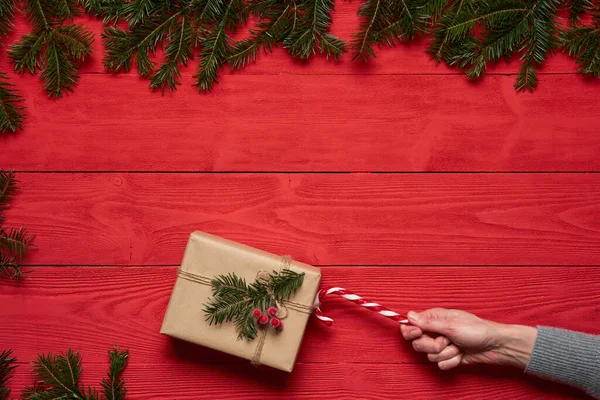 Woman's hand pulling a Christmas present with traditional Christmas candy stick — Stockfoto