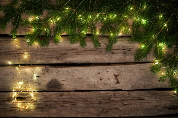 Ramas de árbol de Navidad verde con luces en tablones de madera envejecidos ásperos —  Fotos de Stock