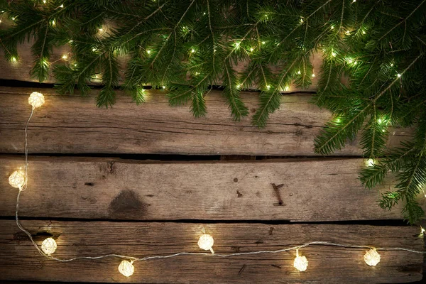 Ramas de árbol de Navidad verde con luces en tablones de madera envejecidos ásperos —  Fotos de Stock