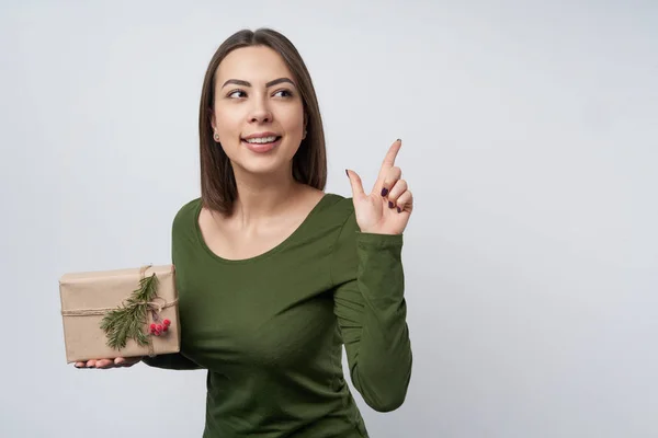 Lycklig flicka håller en presentask insvept i hantverk papper med en gren av gran träd — Stockfoto