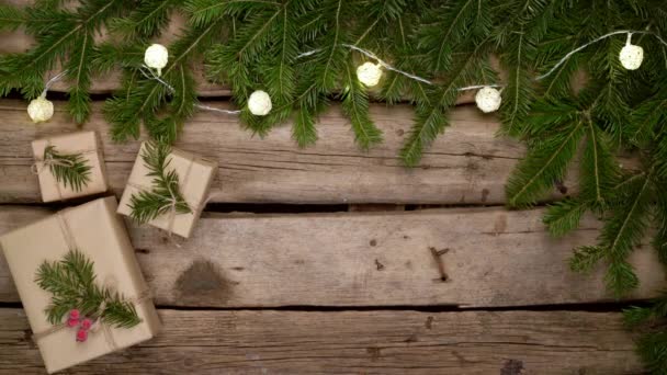 Vánoční rám z jedlových větví s dárkovými krabicemi na bílých prknech — Stock video