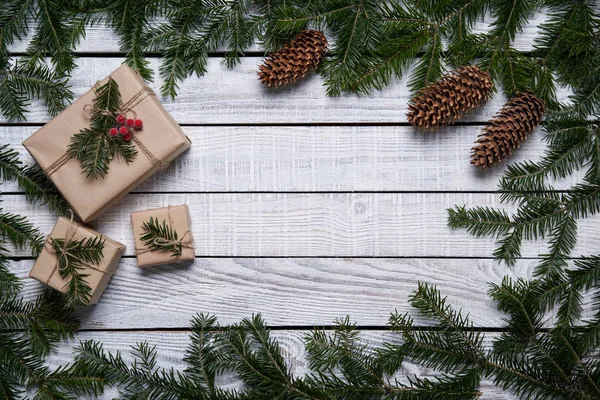 Kerst frame gemaakt van sparren takken met geschenkdoosjes op witte planken — Stockfoto