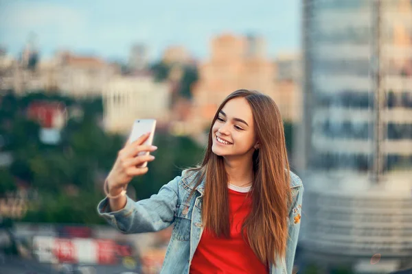 Έφηβη κοπέλα στο φόντο cityscape κάνει αυτο-πορτρέτο με το έξυπνο τηλέφωνό της — Φωτογραφία Αρχείου