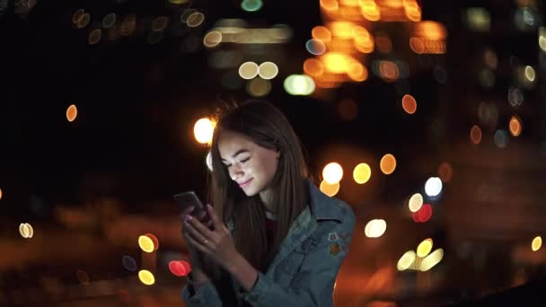 Tiener meisje op stadsgezicht achtergrond met een telefoon in de hand chatten — Stockvideo