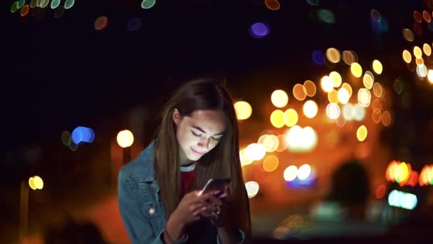 Adolescente chica en el paisaje urbano de fondo sosteniendo un teléfono en la mano charlando — Vídeos de Stock