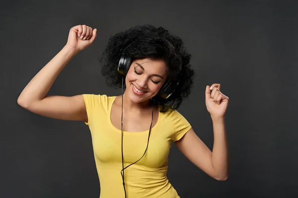 Mujer feliz escuchando música en auriculares y bailando con los ojos cerrados —  Fotos de Stock