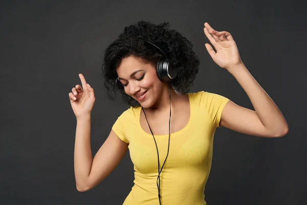 Mujer feliz escuchando música en auriculares y bailando con los ojos cerrados — Foto de Stock