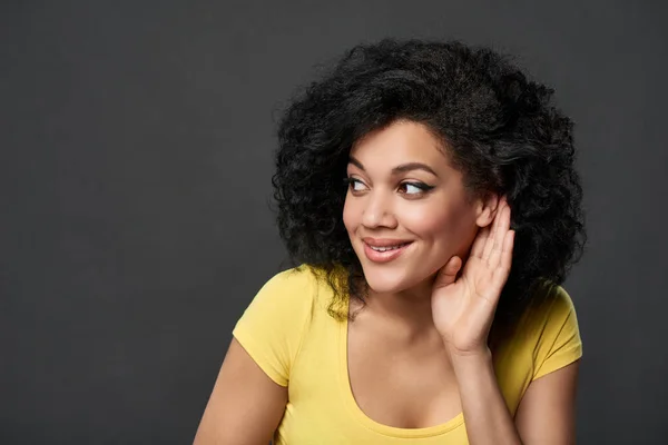 Mulher sorridente ouvindo fofocas com palma blindagem orelha — Fotografia de Stock