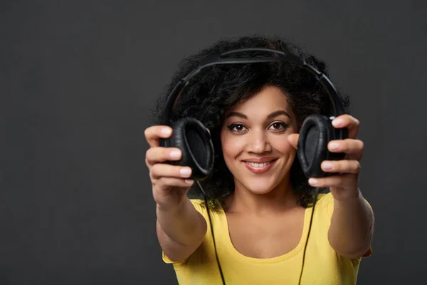 Mulher sorridente dando-lhe fones de ouvido, tiro estúdio — Fotografia de Stock