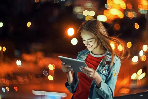 Κορίτσι στο φόντο νύχτα cityscape με φώτα του δρόμου, χρησιμοποιώντας ένα ψηφιακό tablet — Φωτογραφία Αρχείου