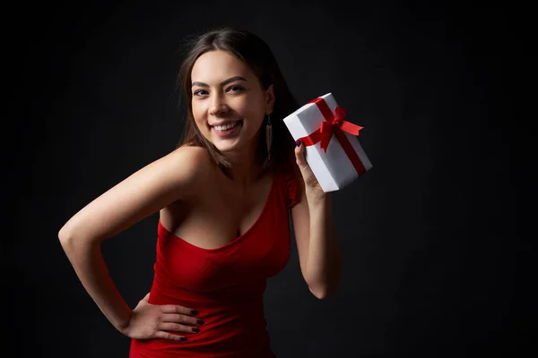 Joyeux flirt femme en robe de soirée rouge montrant une boîte cadeau — Photo