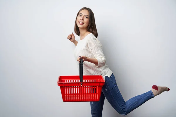 Mulher morena sorridente andando com cesta de compras vazia — Fotografia de Stock