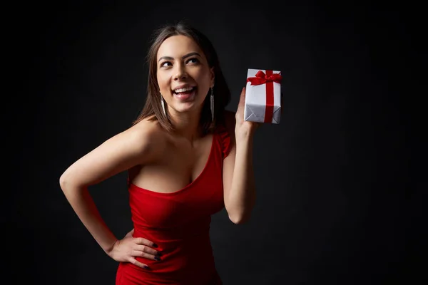 Счастливая Игривая Женщина Красном Вечернем Платье Подарочной Коробкой Глядя Сторону — стоковое фото