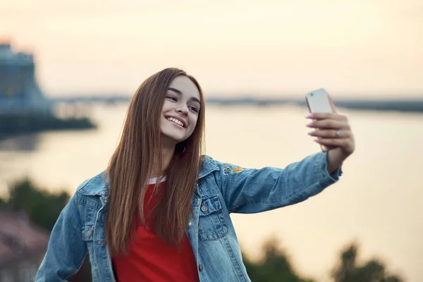 Adolescente menina na paisagem urbana fundo fazendo auto retrato com seu telefone inteligente — Fotografia de Stock