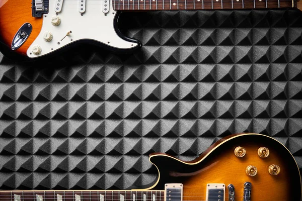 アコースティックフォームパネルの背景にある2つのエレクトリックギターのトップビュー 間のコピースペース — ストック写真