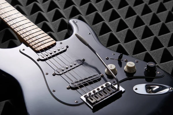 Guitarra elétrica preta deitada no painel de espuma acústica — Fotografia de Stock