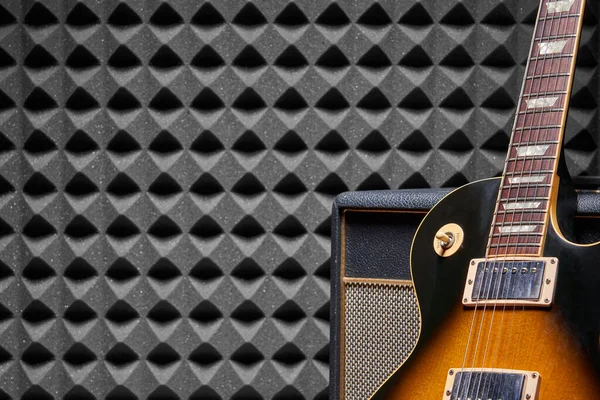 Electric guitar leaning on Guitar Amplifier Combo over acoustic foam panel background — Stock Photo, Image