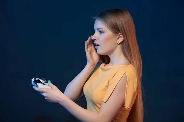 一个女孩用蓝色背景的操纵杆玩电子游戏的简介 — 图库照片