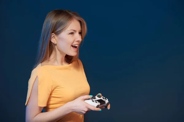 Profil seorang gadis bermain video game dengan joystick di latar belakang biru — Stok Foto